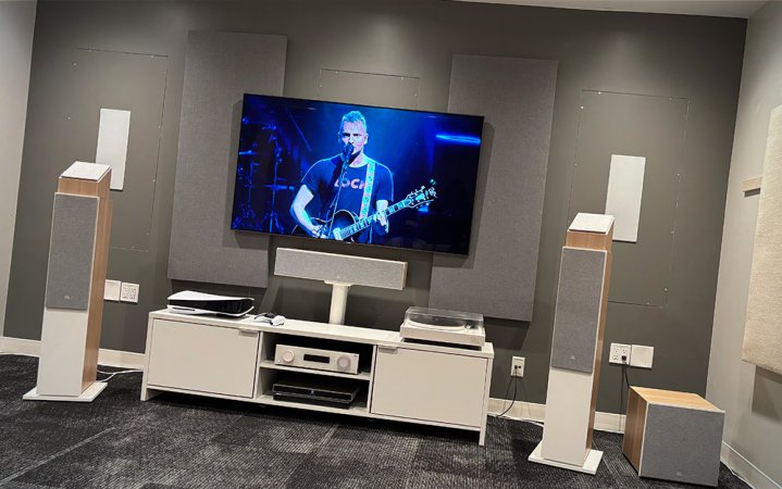   Μεγάφωνα JBL Stage 2 σε χρώμα latte με τηλεόραση σε μια λευκή και γκρι αίθουσα επίδειξης