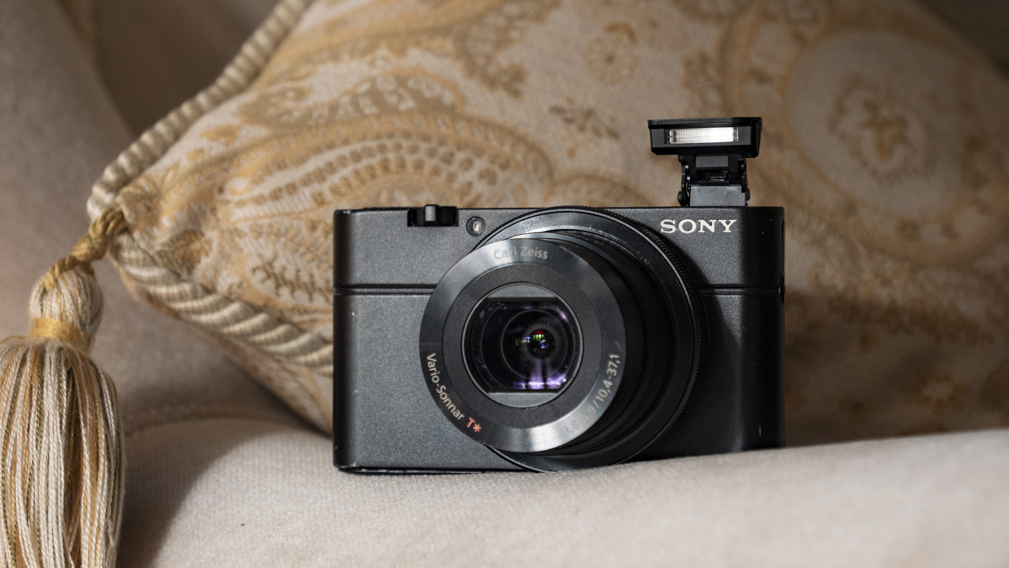 Κάμερα Sony Cybershot RX100 point-and-shoot στο μπράτσο ενός καναπέ